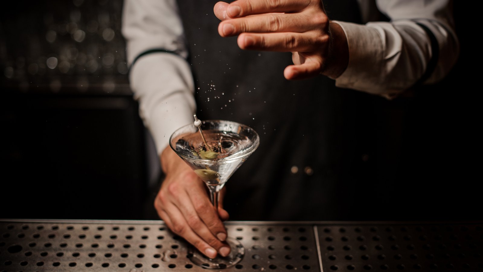 “Bartender preparing a classic martini with olives, capturing the craft and precision behind premium gin cocktails.”