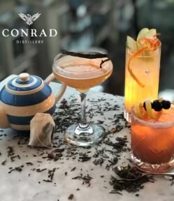 Selection of Conrad G&Tea cocktails with teapot, tea leaves and citrus garnishes on marble table