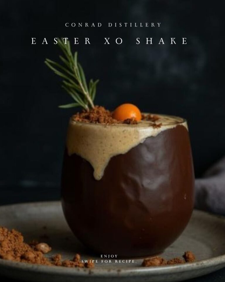Easter XO Shake cocktail in chocolate-lined glass with creamy foam, rosemary and chocolate crumble garnish.