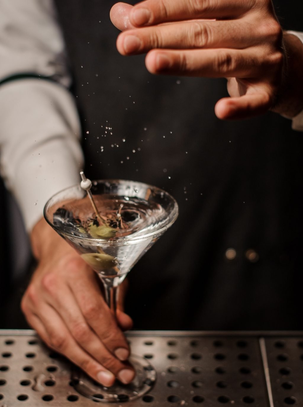 “Bartender preparing a classic martini with olives, capturing the craft and precision behind premium gin cocktails.”
